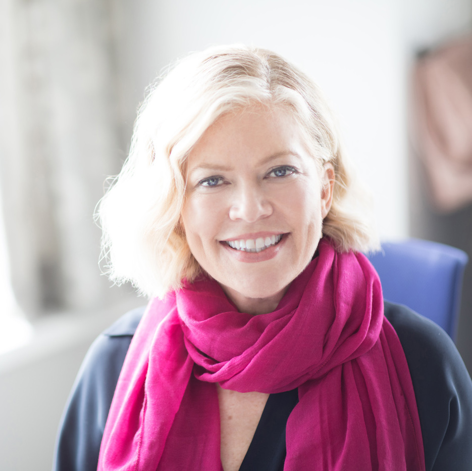 Lisa_Headshot A blond woman smiling to camera with a pink scarf around her neck