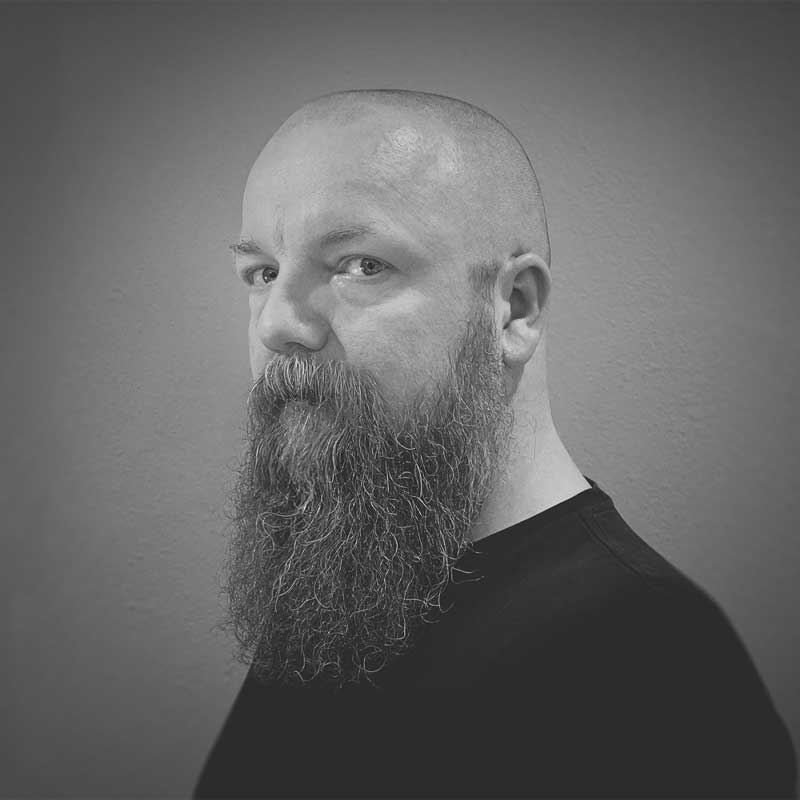 Tomasz_Opasinski Man with hat and a beard smiling with his arm across his body